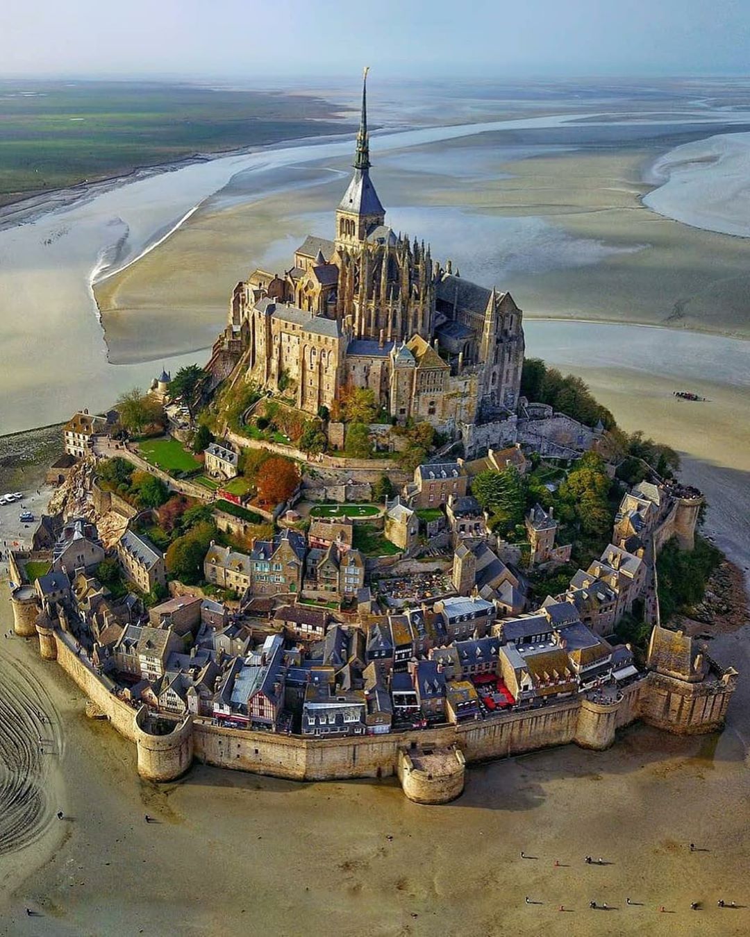 Aerial view of Mont Saint-Michel, a historic island abbey surrounded by tidal flats in Normandy, France, showcasing medieval architecture and stone ramparts