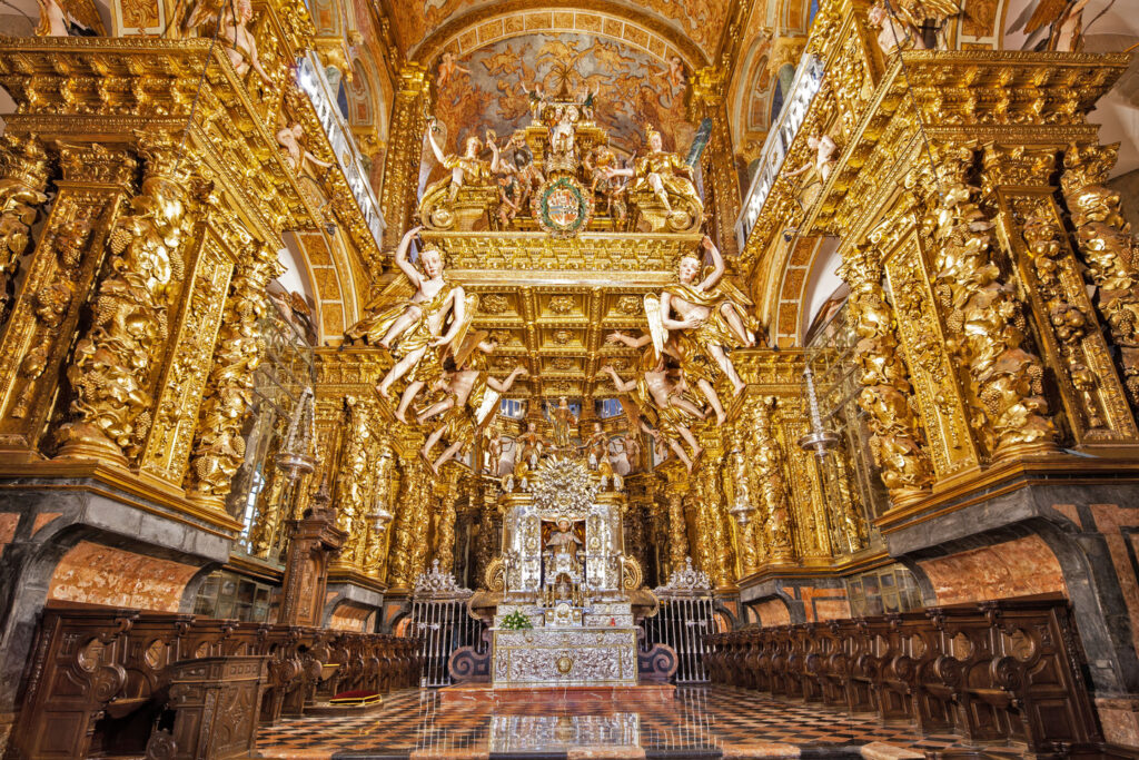 "Ornate golden Baroque altar with angel sculptures inside a historic Catholic church in Spain, showcasing intricate religious art and architecture"