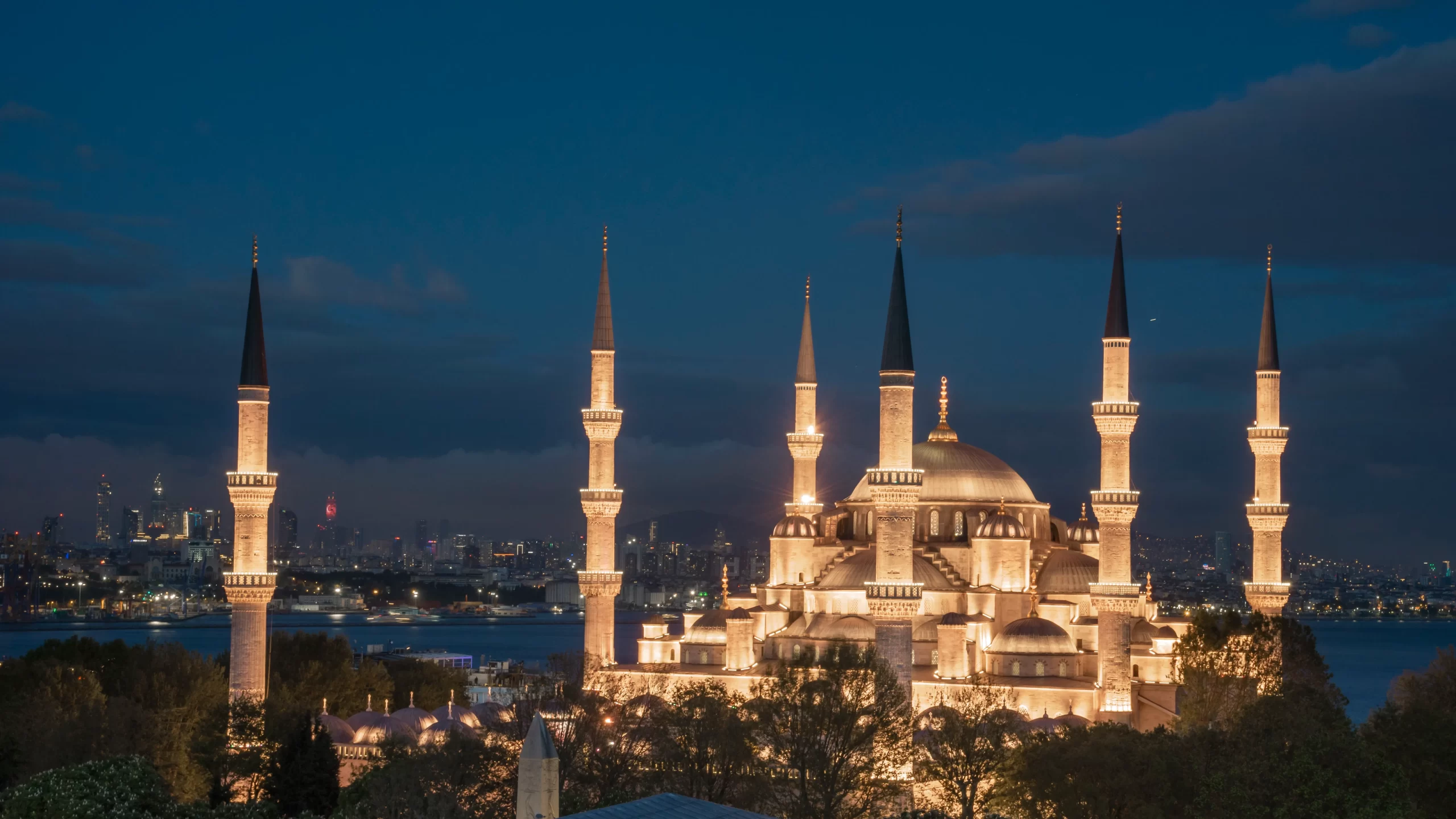 “The Blue Mosque in Istanbul, Turkey, beautifully illuminated at night with six minarets and the city skyline in the background.”