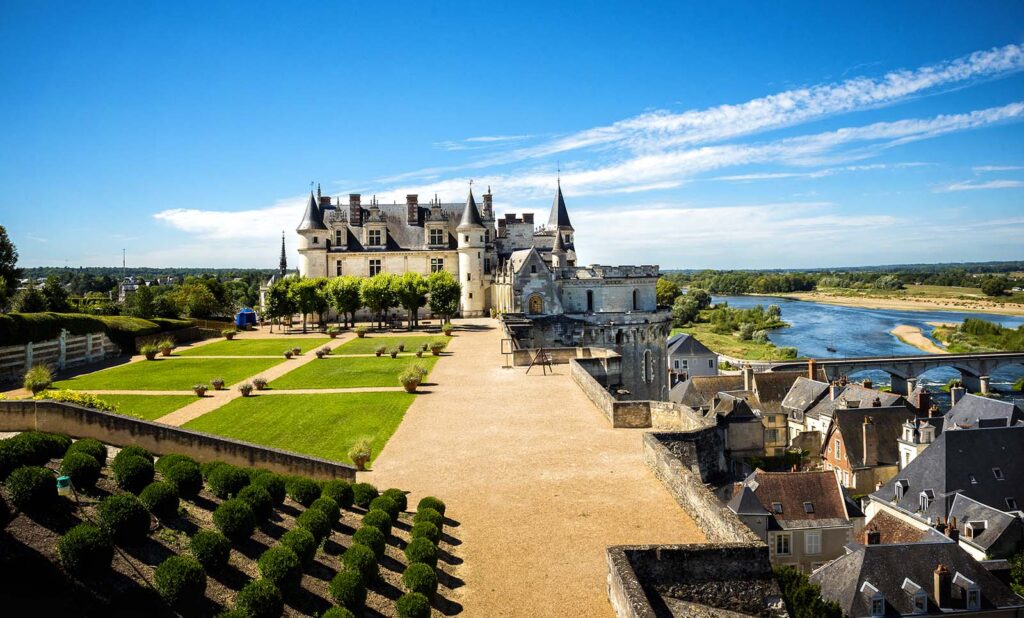 "Chateau d’Amboise in the Loire Valley, France, with manicured gardens and panoramic views of the Loire River and historic village rooftops under a clear blue sky"