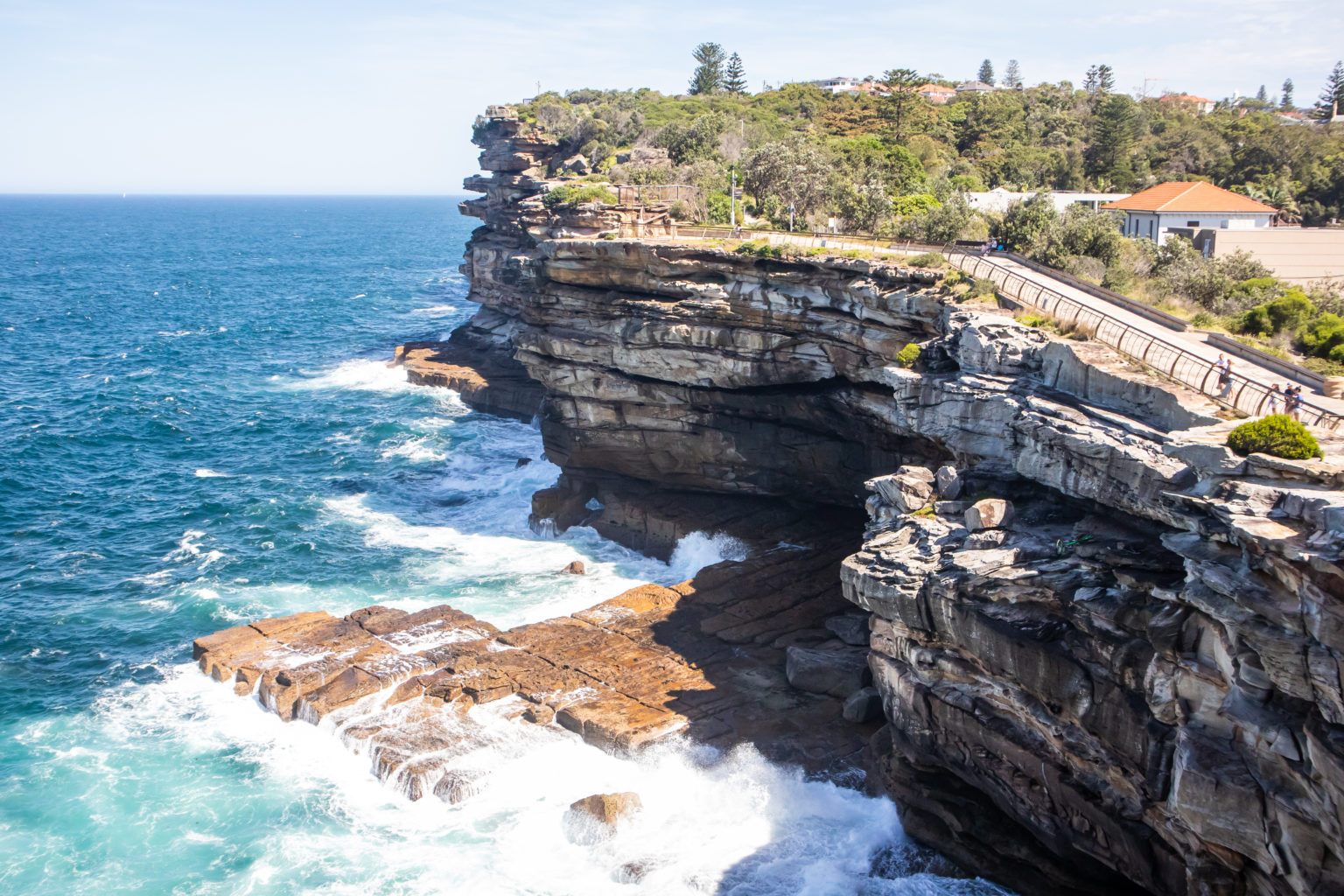 Dramatic sea cliffs at Watsons Bay in Sydney, Australia with ocean waves crashing against the rocks and a scenic walkway above