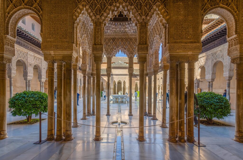 "Intricately carved Moorish arches and columns of the Court of the Lions at the Alhambra palace in Granada, Spain, showcasing Islamic architecture and ornamental stucco work"