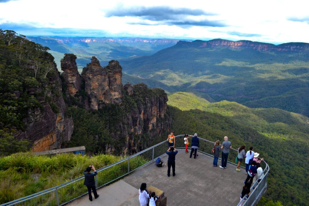 Nature meets urban life in Sydney: Tourists enjoying panoramic views of the Three Sisters rock formation and Jamison Valley from Echo Point lookout in the Blue Mountains, Australia