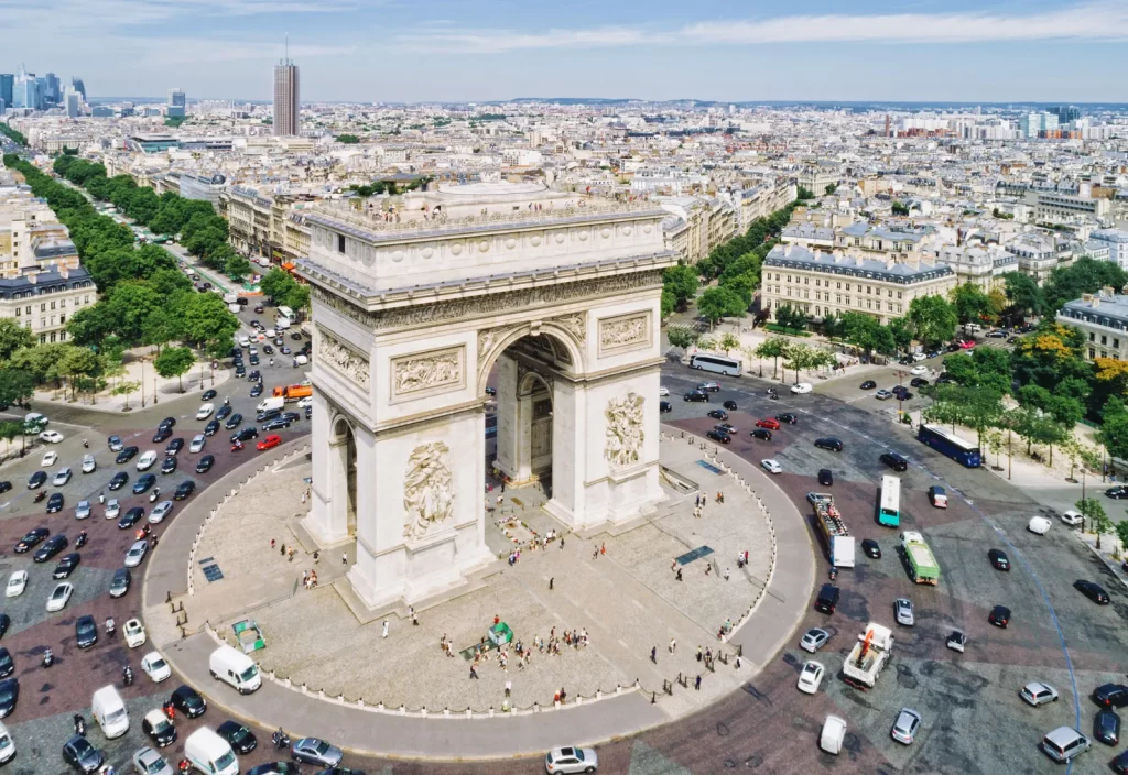 Aerial view of the Arc de Triomphe in Paris, France, surrounded by the bustling traffic of Place Charles de Gaulle and panoramic cityscape
