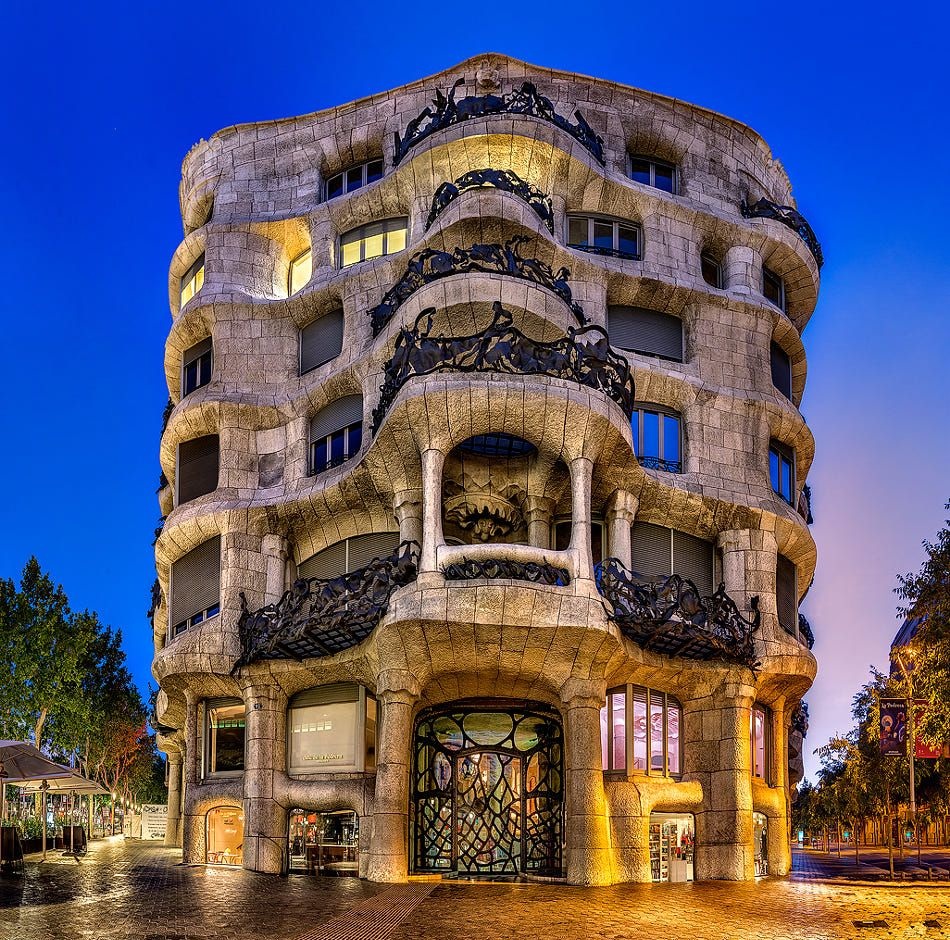 Sagrada Familia Barcelona guide: "Front view of Casa Mila, also known as La Pedrera, a modernist residential building by Antoni Gaudí in Barcelona, Spain, illuminated at twilight"