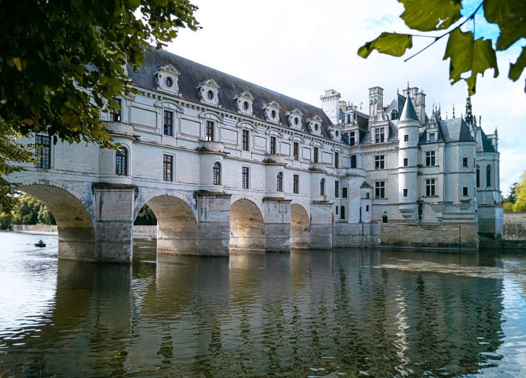 "Chateau de Chenonceau in the Loire Valley, France, reflecting on the River Cher with elegant arches and Renaissance architecture surrounded by trees"