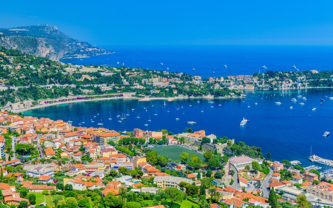 Aerial view of Villefranche-sur-Mer on the French Riviera with colorful rooftops, yachts in the bay, and lush hills along the Mediterranean coastline