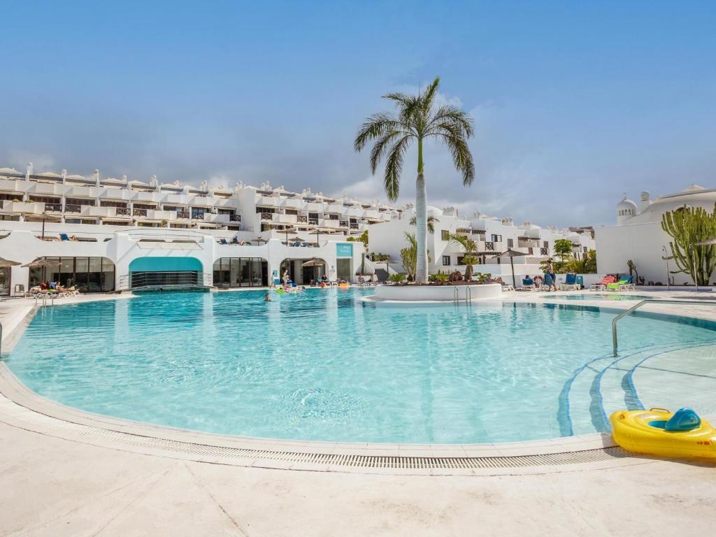 "Luxury beachfront resort with palm tree and large outdoor swimming pool in Tulum, Mexico, on a sunny day"