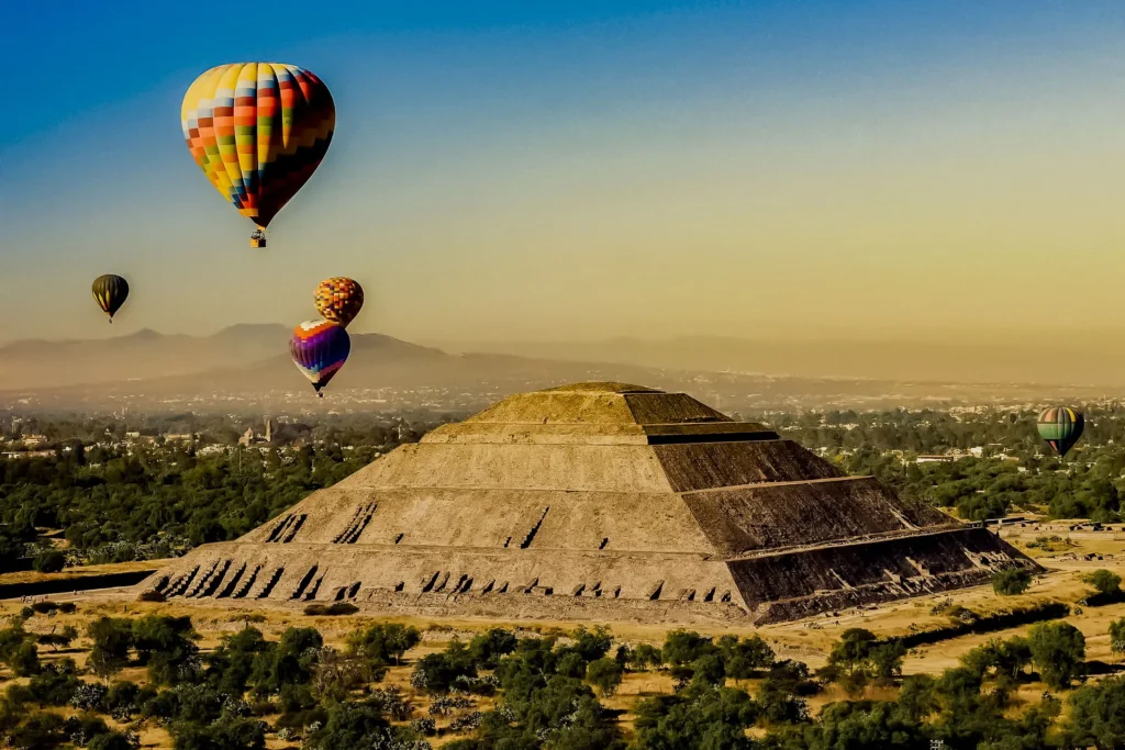 Teotihuacan City of the Gods: "Colorful hot air balloons flying over the Pyramid of the Sun at Teotihuacan during sunrise in Mexico"