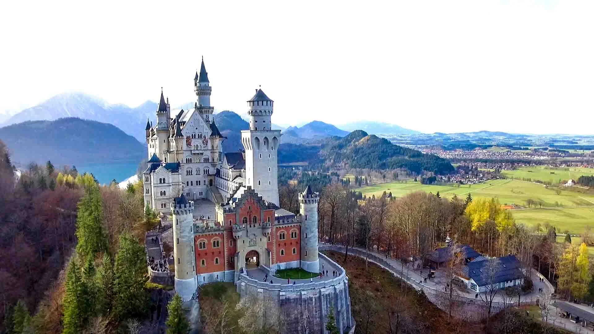 "Aerial view of Neuschwanstein Castle in Bavaria, Germany, surrounded by alpine forests and scenic countryside on a clear day"