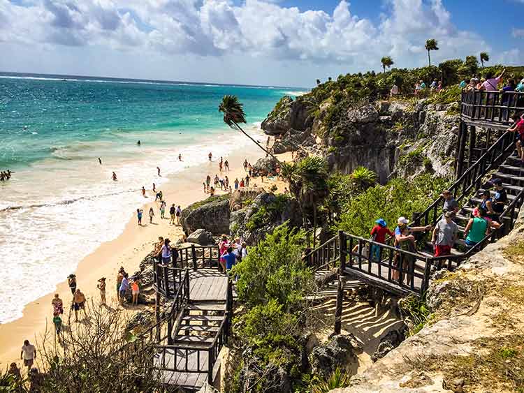 Tulum ruins and beaches: "Tourists exploring the cliffside staircase leading to the beach below the Tulum Ruins on the Caribbean coast in Riviera Maya, Mexico"