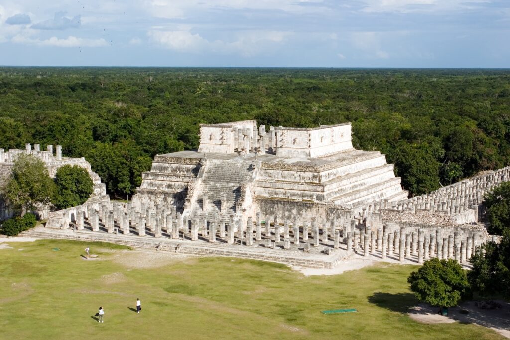 "Temple of the Warriors and the Group of a Thousand Columns at Chichen Itza, Mexico, surrounded by jungle and open green space"
