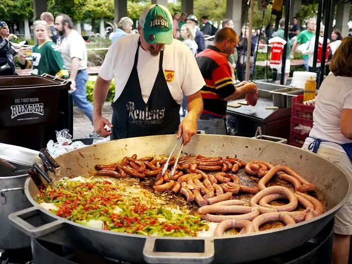 "A street food vendor grilling German sausages and vegetables in a large pan at an outdoor Oktoberfest-style festival in Germany" Oktoberfest in Munich