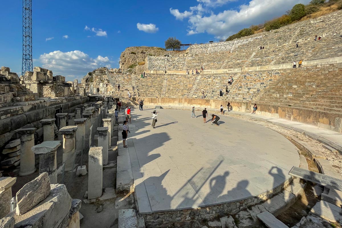 "Ancient Great Theatre of Ephesus in Turkey with visitors exploring the Roman amphitheater under a bright blue sky"