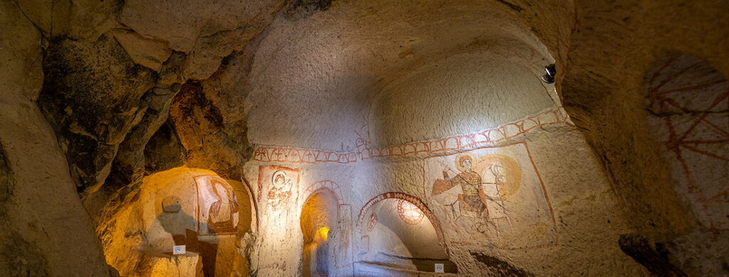 "Ancient frescoes inside a rock-cut church at the Göreme Open-Air Museum in Cappadocia, Turkey, showcasing Byzantine Christian art carved into volcanic rock"