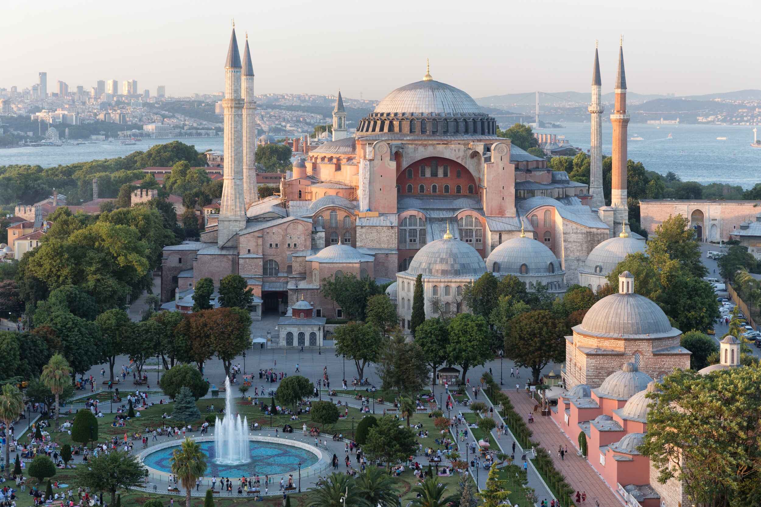 "Aerial view of Hagia Sophia in Istanbul, Turkey, with its domes, minarets, and surrounding gardens overlooking the Bosphorus Strait at sunset"