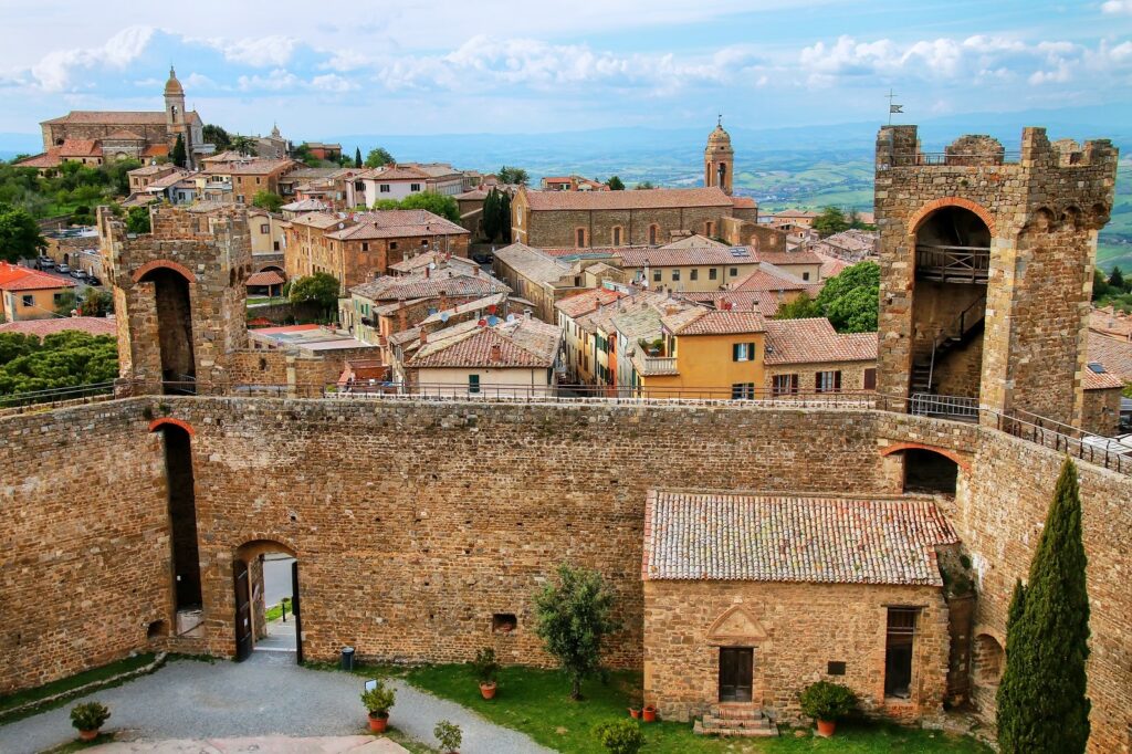 "Historic hilltop town of Montalcino in Tuscany, Italy, featuring medieval stone walls, towers, and terracotta rooftops overlooking the scenic countryside"