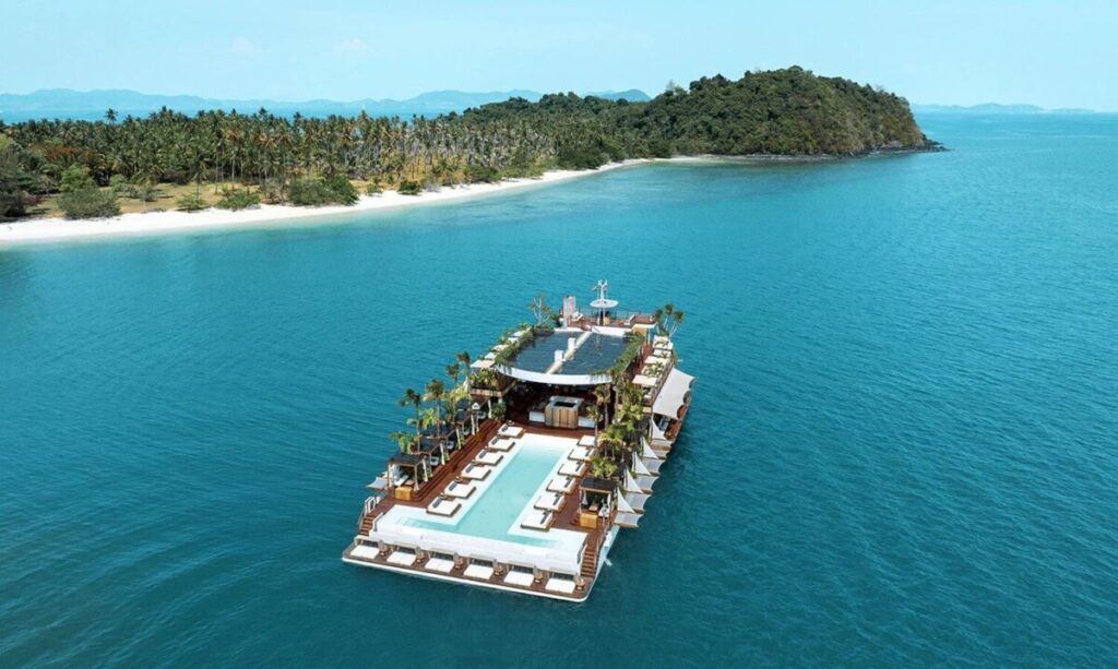 "Luxury floating beach club with swimming pool surrounded by turquoise waters near a tropical island in Thailand"