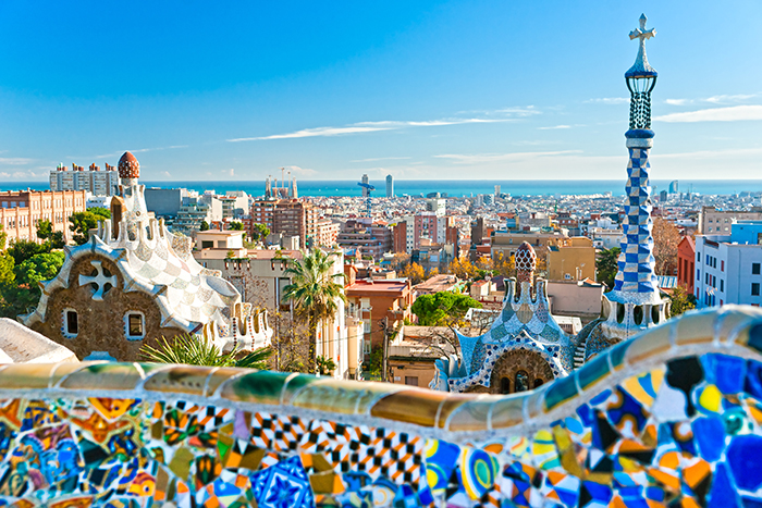 Park Güell travel guide Barcelona: "Panoramic view of Barcelona city from Park Güell featuring colorful mosaic architecture and Mediterranean Sea skyline in Spain."