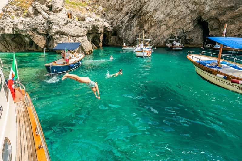 Amalfi Coast Italy: "Tourists swimming and diving from boats in the clear turquoise waters near sea caves along the Amalfi Coast in southern Italy"