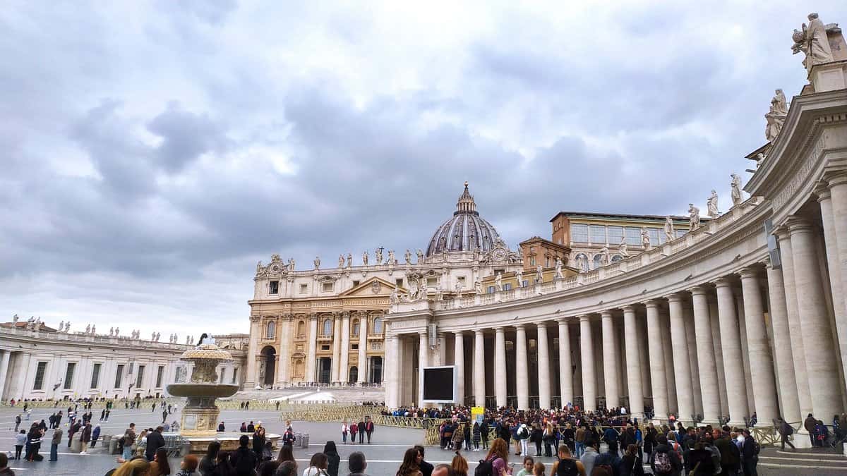 "Crowds gathered at St. Peter’s Square in Vatican City with St. Peter’s Basilica and its iconic dome under a cloudy sky in Rome, Italy"