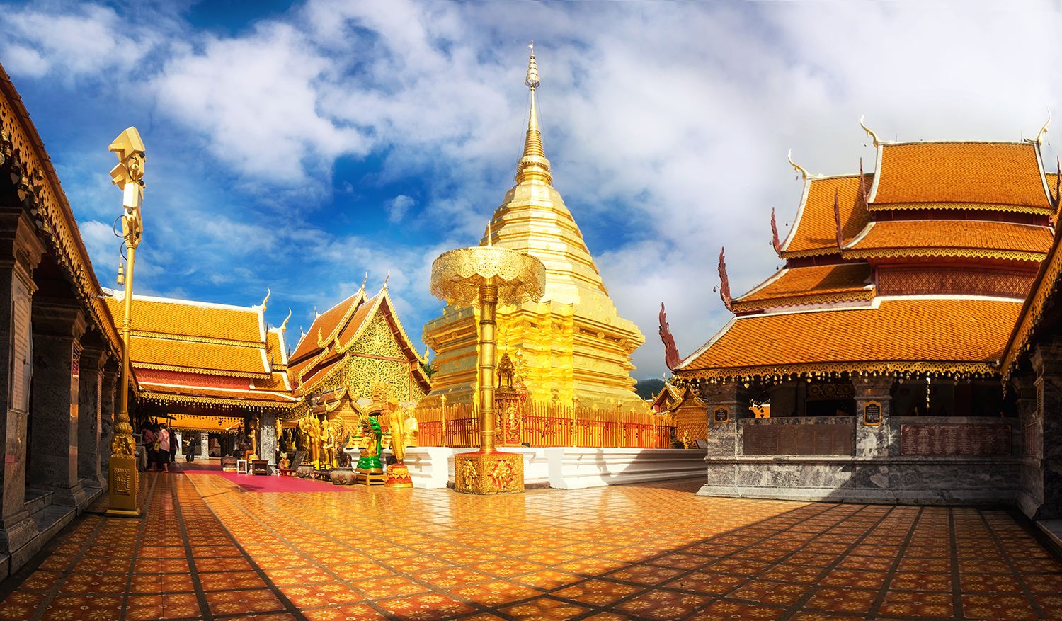 Chiang Mai temples: "Golden chedi and intricate temple structures of Wat Phra That Doi Suthep in Chiang Mai, Thailand, under a vibrant blue sky"