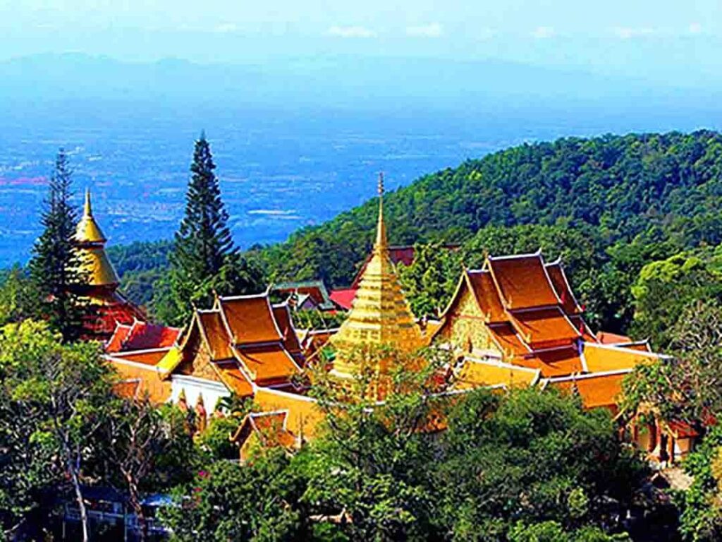 "Aerial view of Wat Phra That Doi Suthep, a golden temple complex in Chiang Mai, Thailand, surrounded by lush forested mountains and panoramic views"