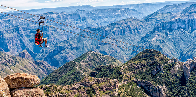 Copper Canyon Mexico "Tourist ziplining over Copper Canyon in Chihuahua, Mexico, with panoramic views of rugged mountains and deep gorges in the background"