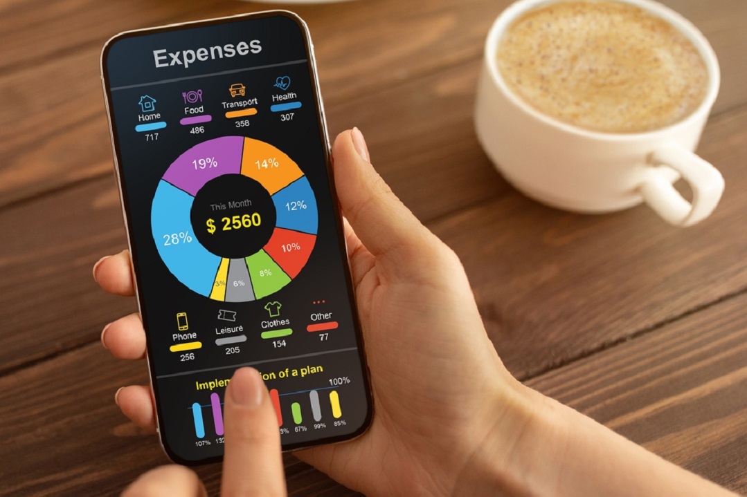 “Person using a smartphone expense tracker app showing a colorful spending chart with categories like home, food, transport, and health, symbolizing personal finance management and budgeting.”