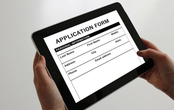 Person filling out an online application form on a tablet for UGC NET December 2025 registration.