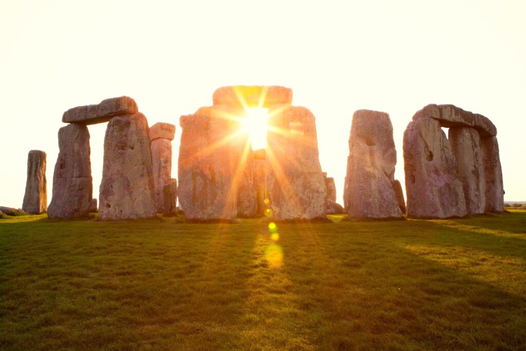 Stonehenge travel guide: "Sunrise shining through the ancient stone pillars of Stonehenge in Wiltshire, England, highlighting the prehistoric monument’s alignment with the summer solstice"